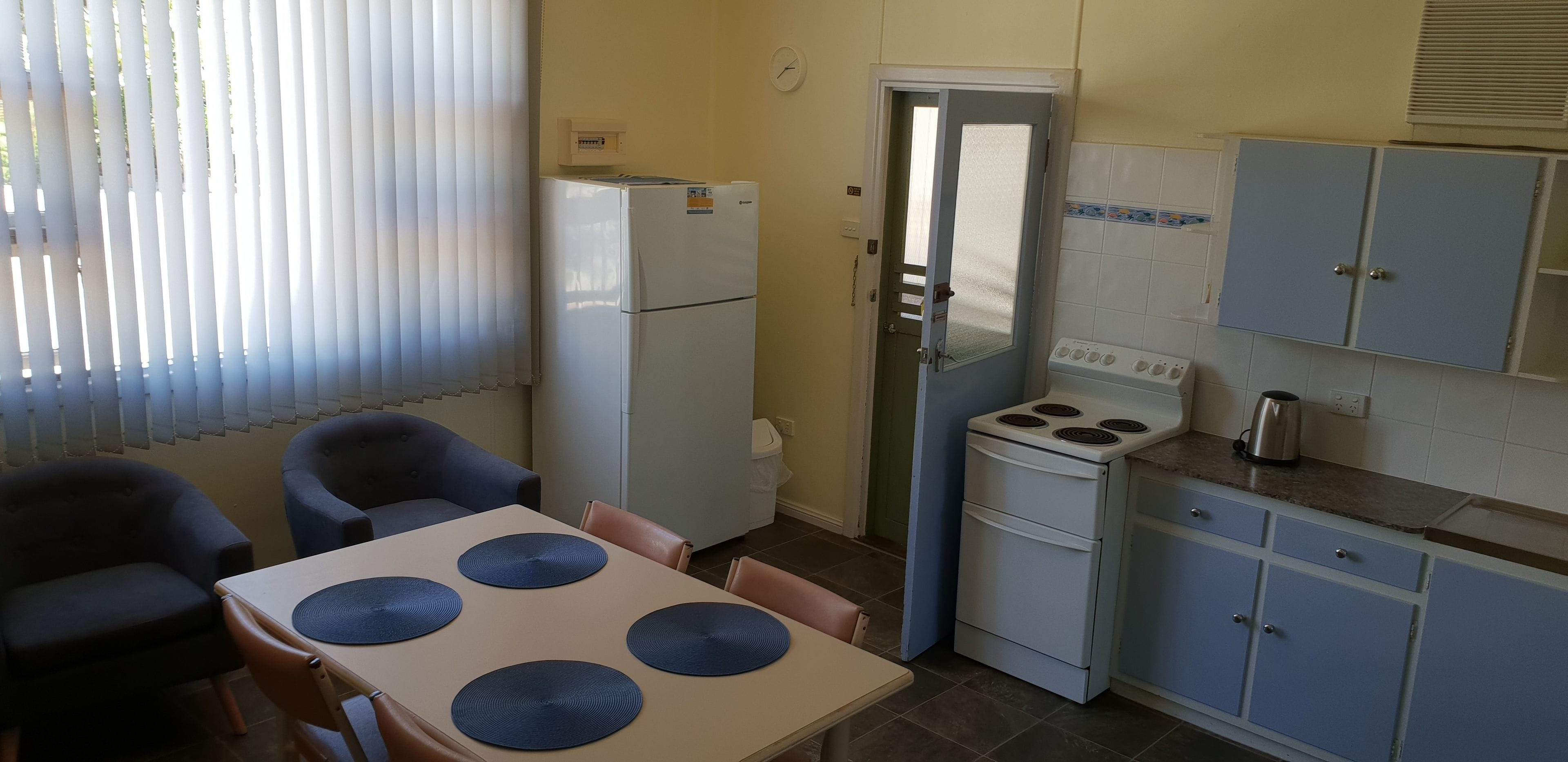 A compact kitchen with a refrigerator, stove, and cabinets.