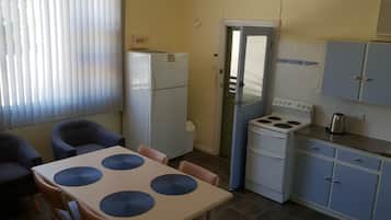 A compact kitchen with a refrigerator, stove, and cabinets.
