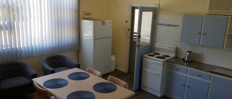 A compact kitchen with a refrigerator, stove, and cabinets.