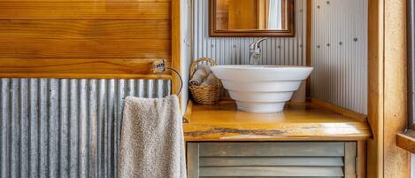 A bathroom with a wooden vanity, a white sink, a towel hanging on a rack, and a mirror.
