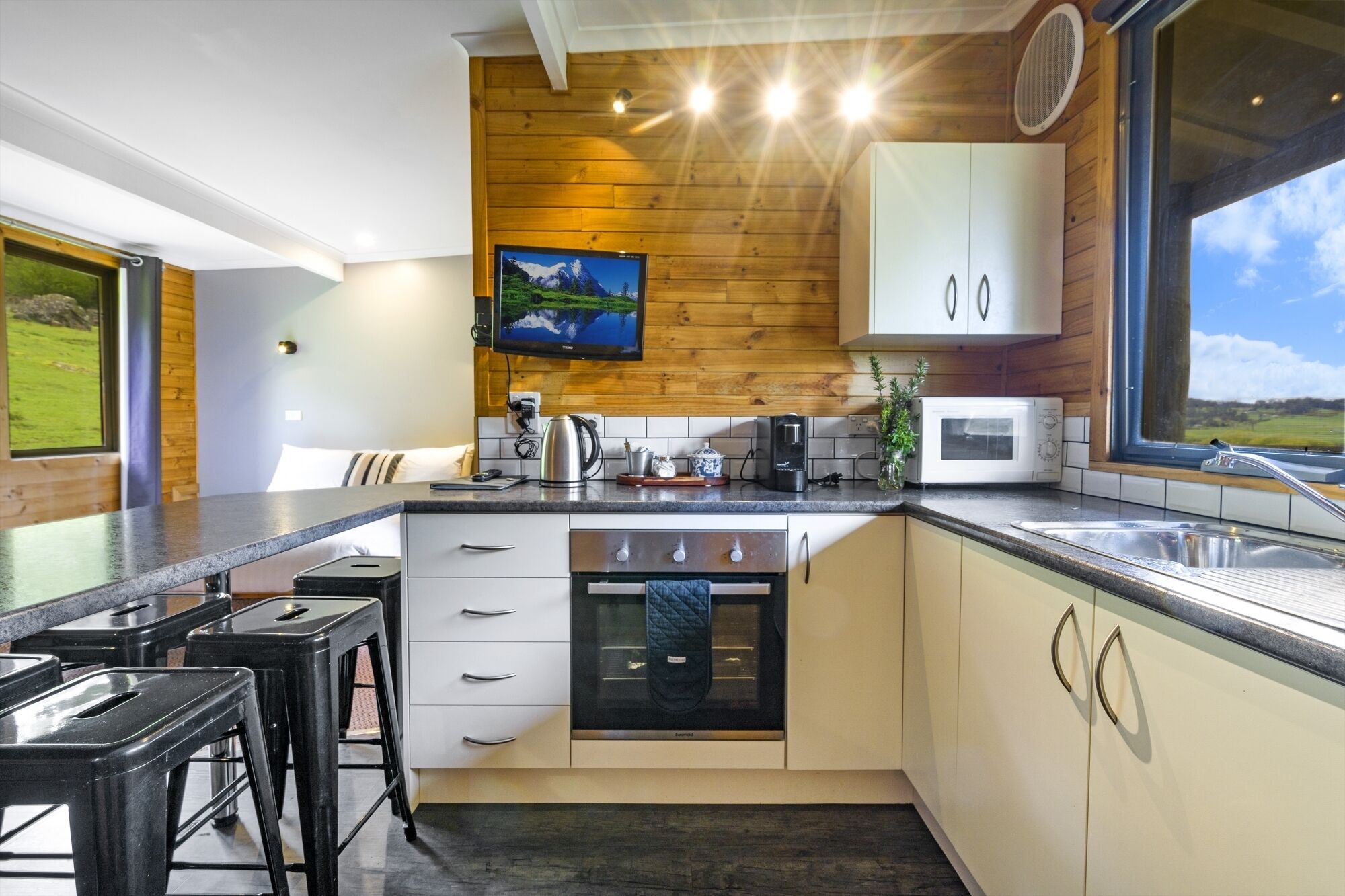Une cuisine moderne agrémentée de touches de bois, dotée d’une grande fenêtre et offrant une vue sur l’extérieur.