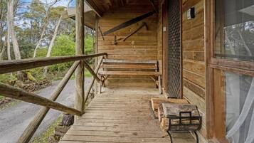 A wooden cabin with a wooden staircase leading to a porch.