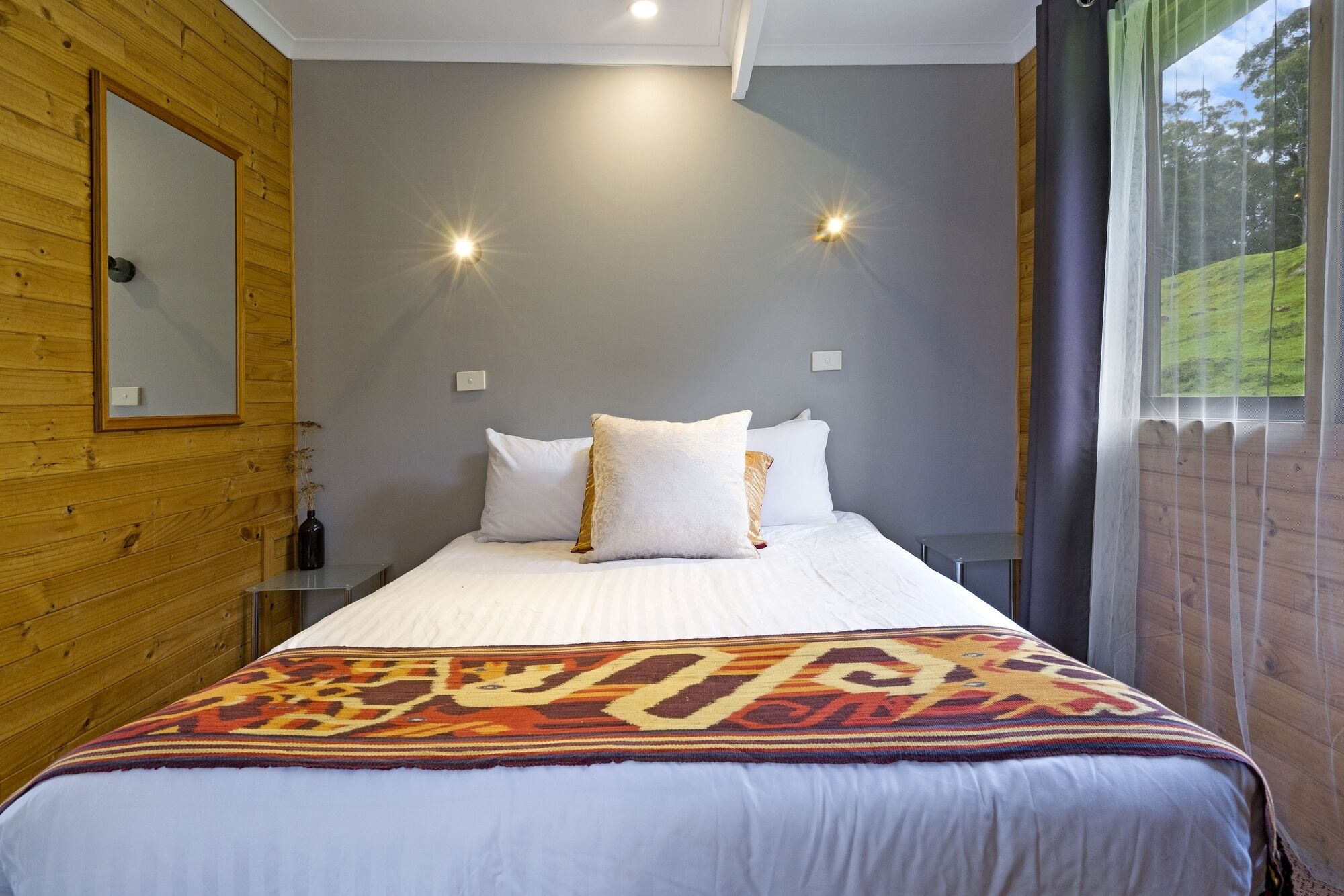 Ein Schlafzimmer mit einem Bett, einem Spiegel und zwei Wandleuchten.