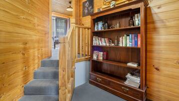 A wooden interior with a bookshelf, a staircase, and a window.