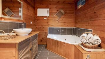 A wooden cabin bathroom with a sink, a bathtub, and a towel basket.