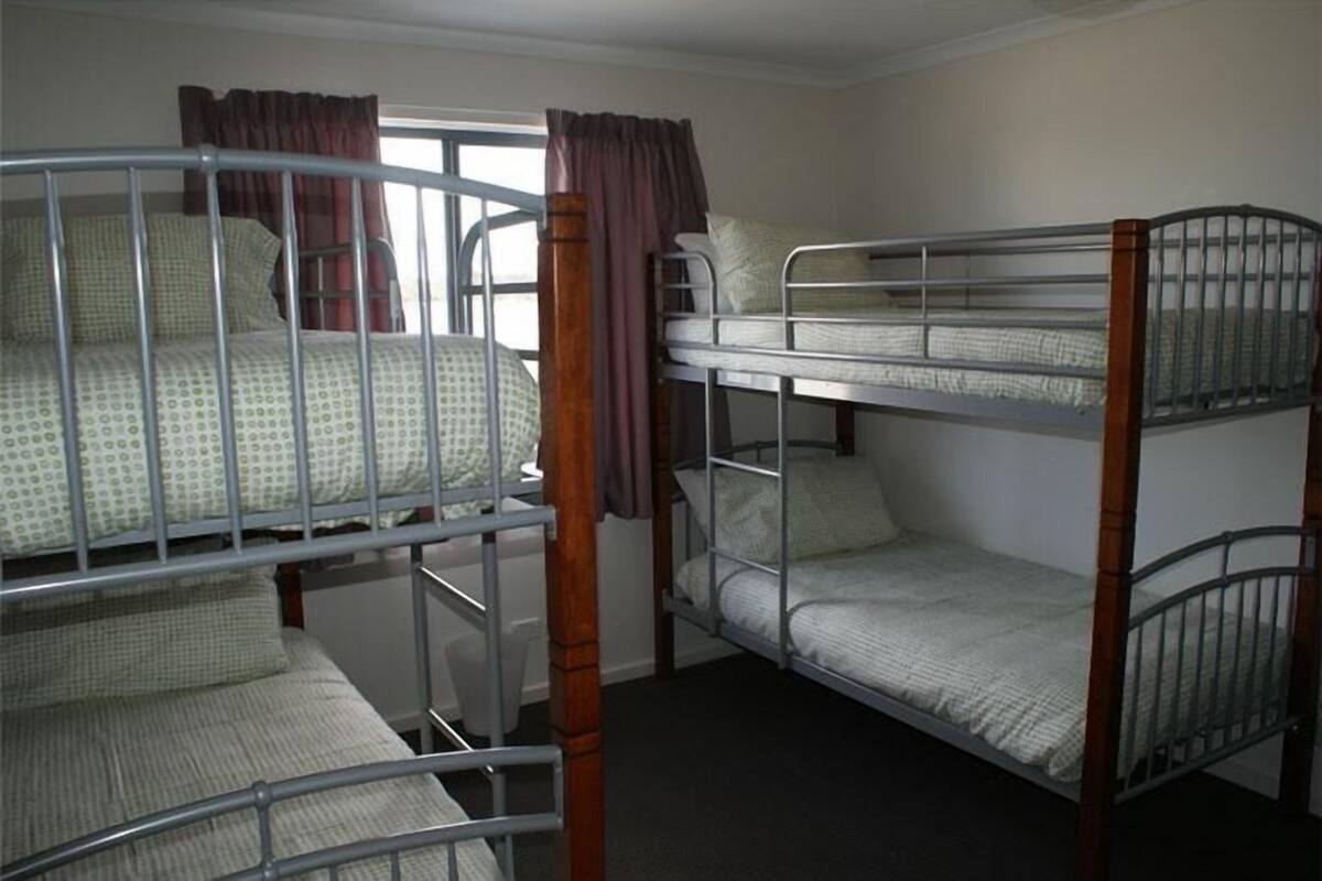 A bunk bed room with a window and curtains.