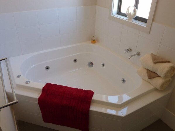 A modern bathroom with a freestanding bathtub, a window with a view, and a towel rack with towels. - Oysta La Vista (Stansbury)