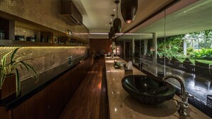 Un baño moderno con un lavamanos grande, estantes de madera y una mampara de vidrio.
