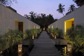A pathway flanked by two buildings with open doors, leading to a central point. - The Diwa Club by Alila Diwa Goa - A Hyatt Brand (Majorda)