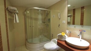 A bathroom with a glass-enclosed shower, a white toilet, and a sink with a mirror above it. -  Parijatha Gateway (Bengaluru)