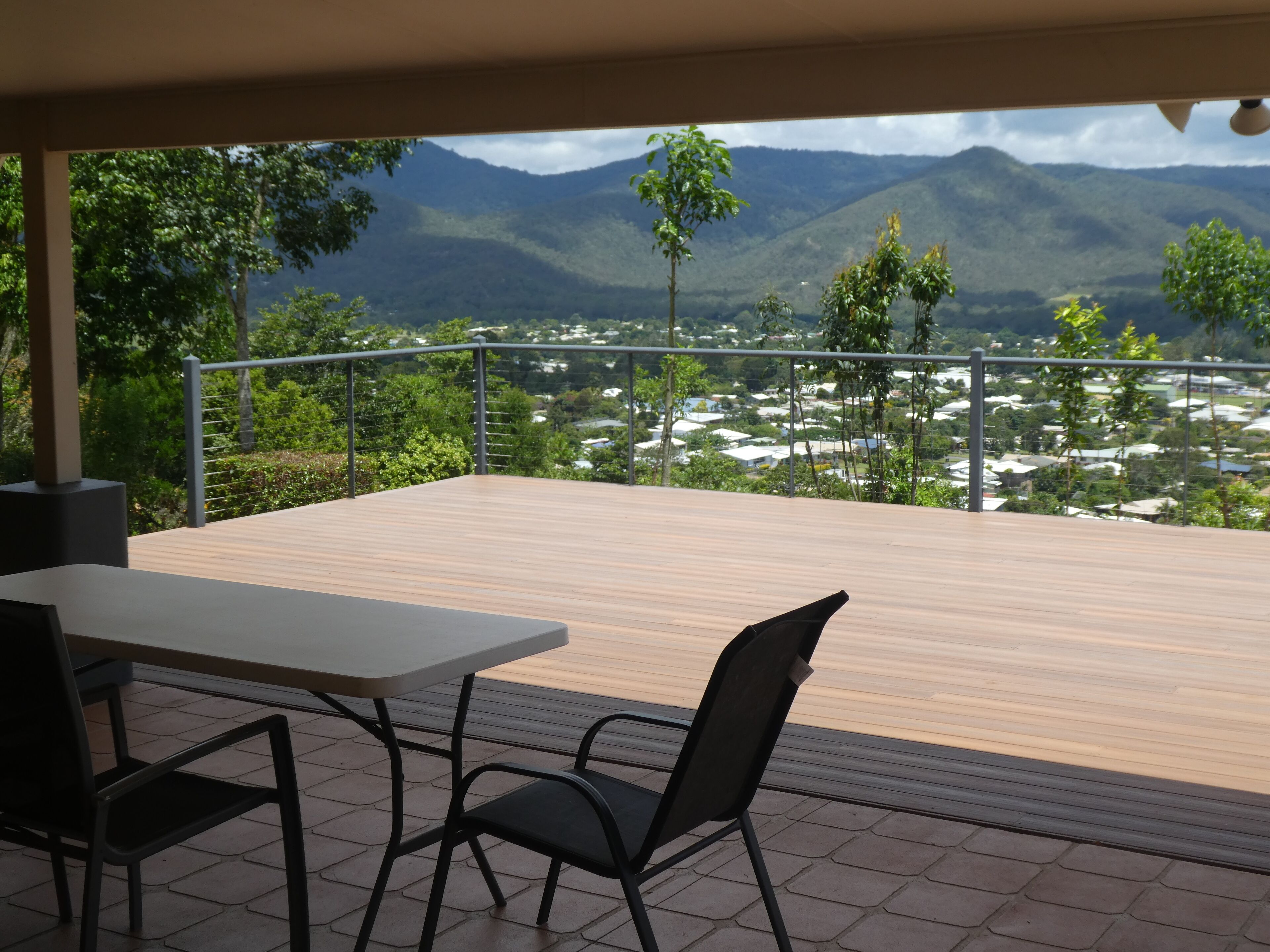 A terrace with a table and chairs, overlooking a mountainous landscape with a view of a town below.
