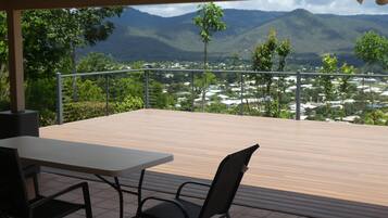 A terrace with a table and chairs, overlooking a mountainous landscape with a view of a town below.