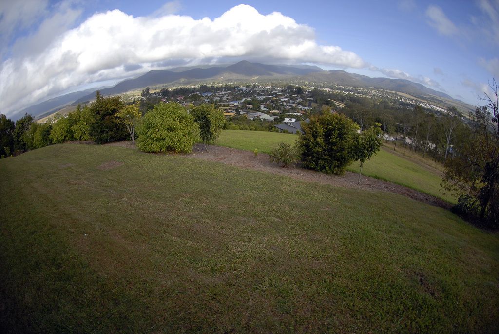A panoramic view of a hilly landscape with a town in the distance, surrounded by trees and open grassy areas.