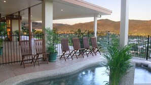 A covered outdoor area with a pool, wooden chairs, and potted plants. - The Summit Rainforest Retreat (Atherton)
