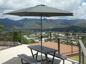 A patio with a picnic table and umbrella, overlooking a town and mountains. - The Summit Rainforest Retreat (Atherton)