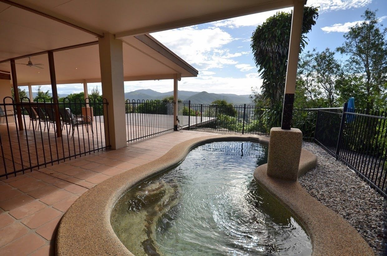 A covered outdoor area with a small pool, seating, and a view of mountains.