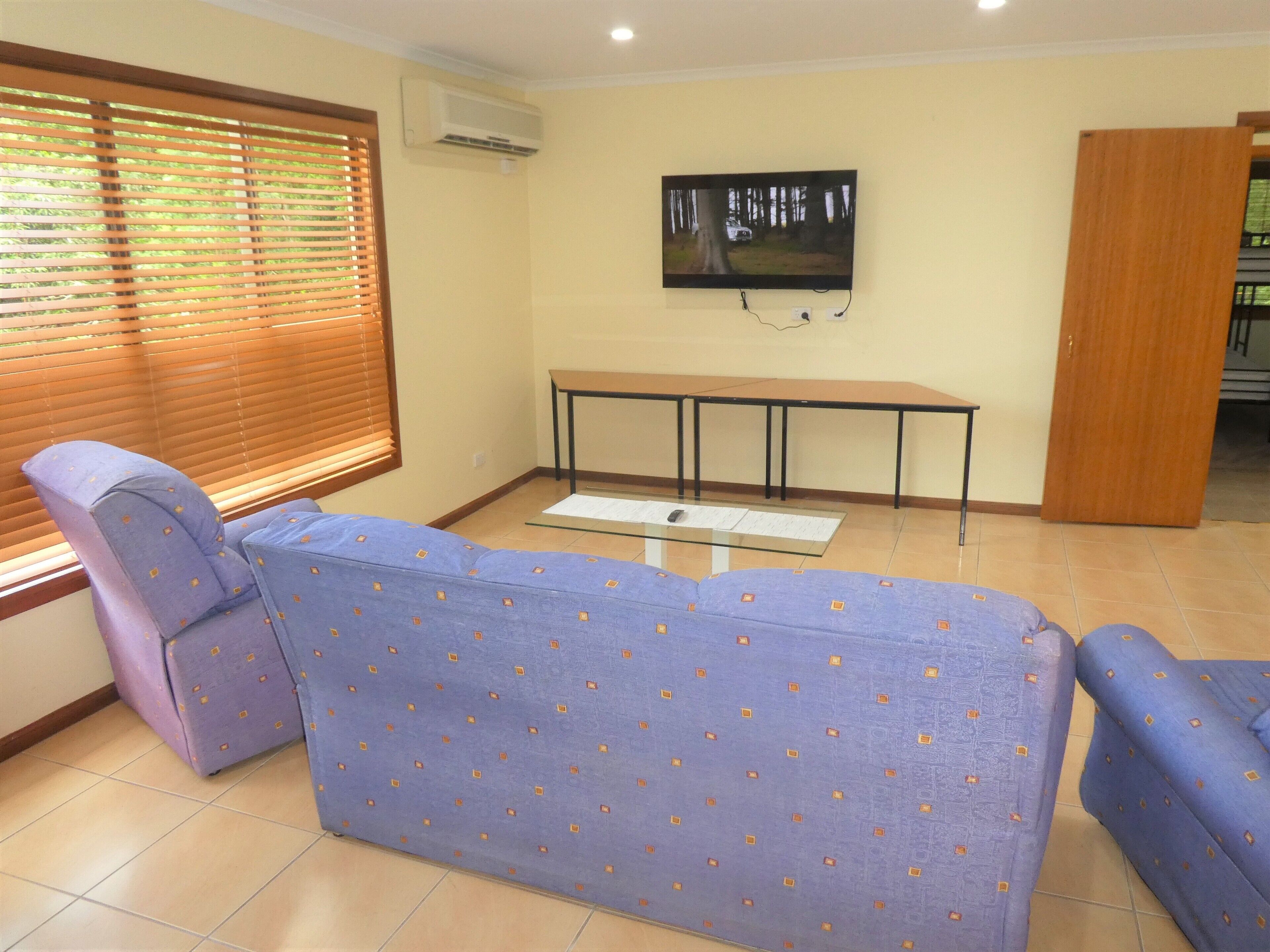 A living room with a sofa, a table, and a TV mounted on the wall.