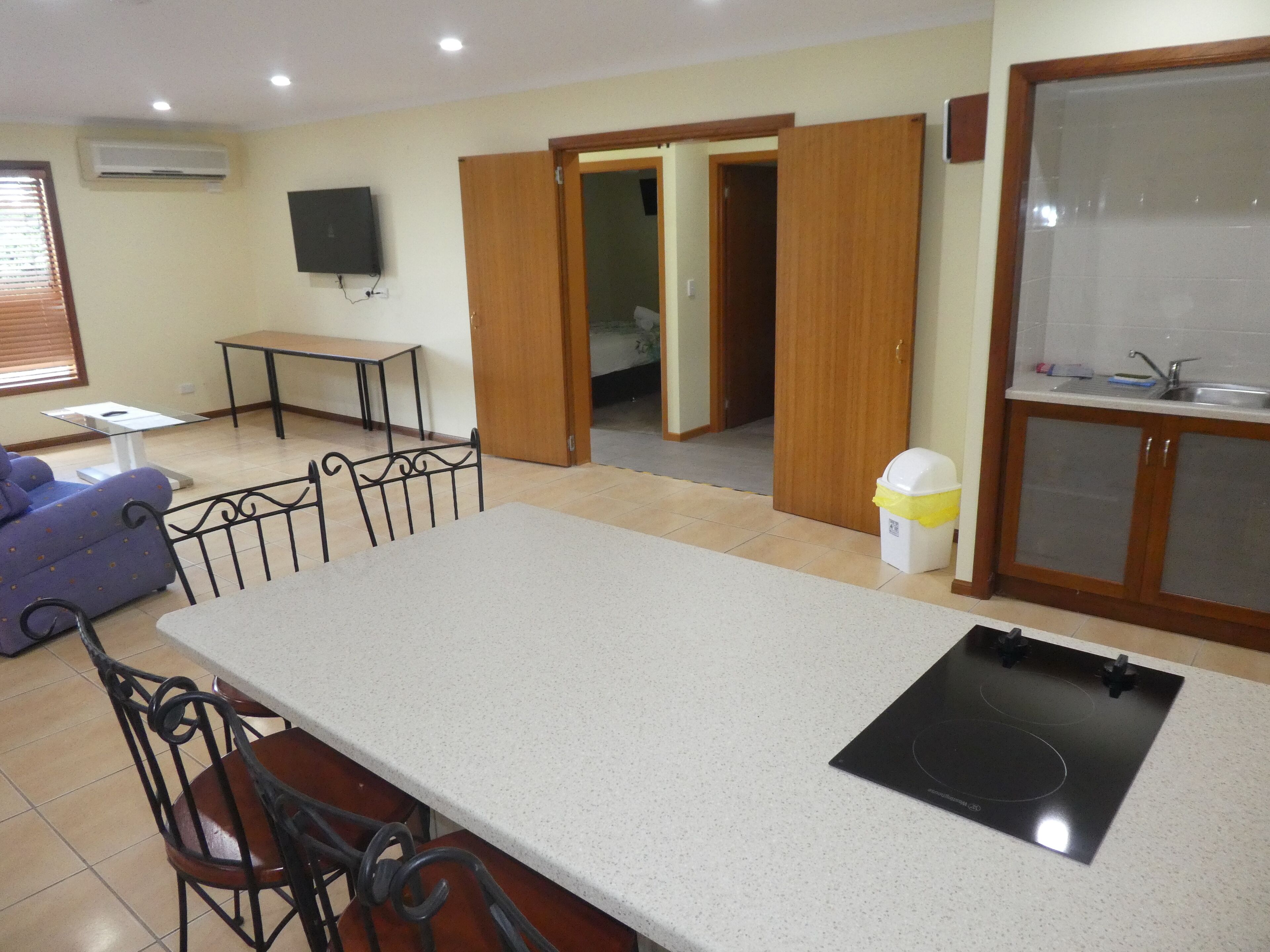 A kitchen with a countertop, sink, and stove. There is a dining area with chairs and a table.