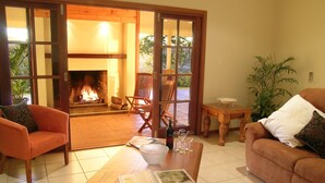 A cozy living room with a fireplace, comfortable seating, and a dining area. - The Summit Rainforest Retreat (Atherton)