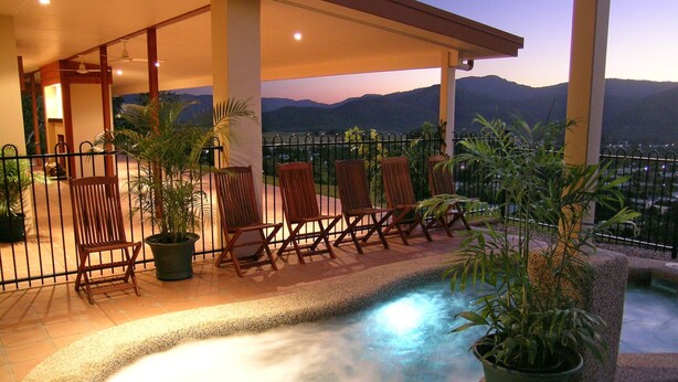A hot tub area with chairs and potted plants, overlooking a mountainous landscape. - The Summit Rainforest Retreat (Atherton)
