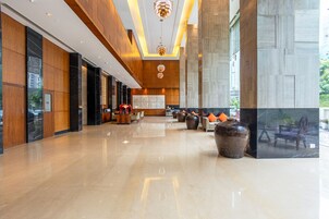 A spacious lobby with a reception desk, seating area, and large windows.