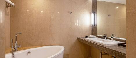 A modern bathroom with a freestanding bathtub, two sinks, and a large mirror.