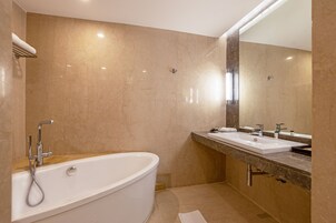 Un baño moderno con una bañera independiente, dos lavamanos y un espejo grande.