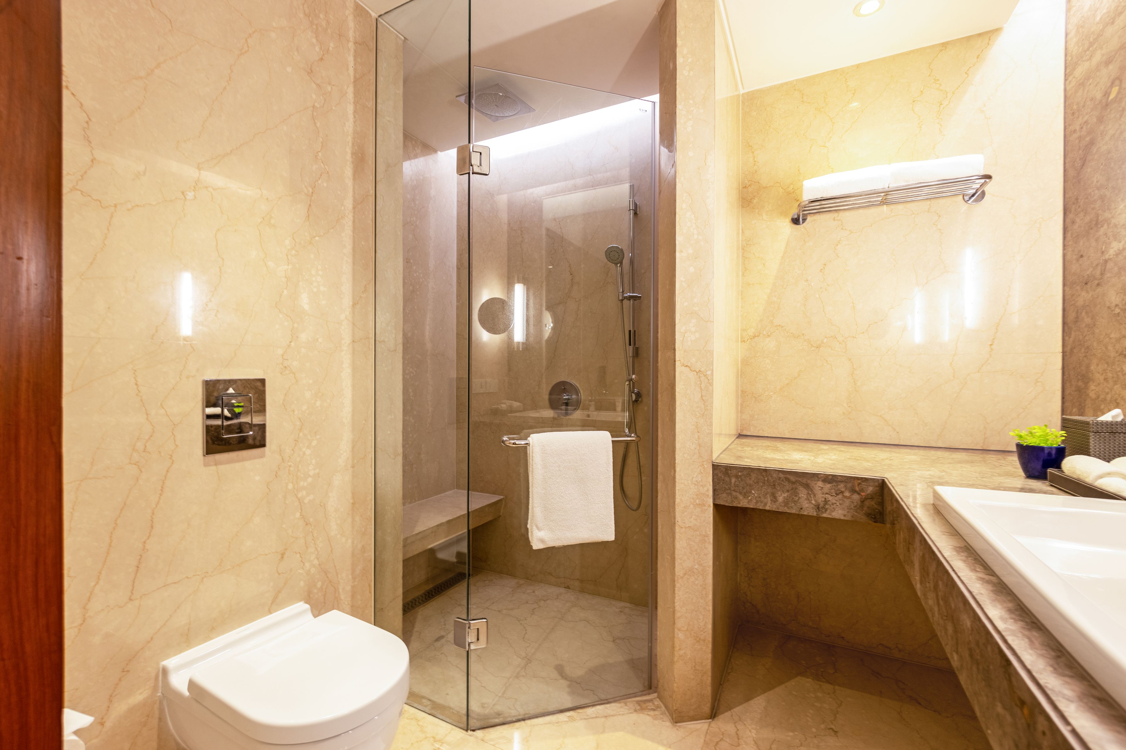 Un baño moderno con ducha envuelta en vidrio, inodoro, lavamanos y espejo.