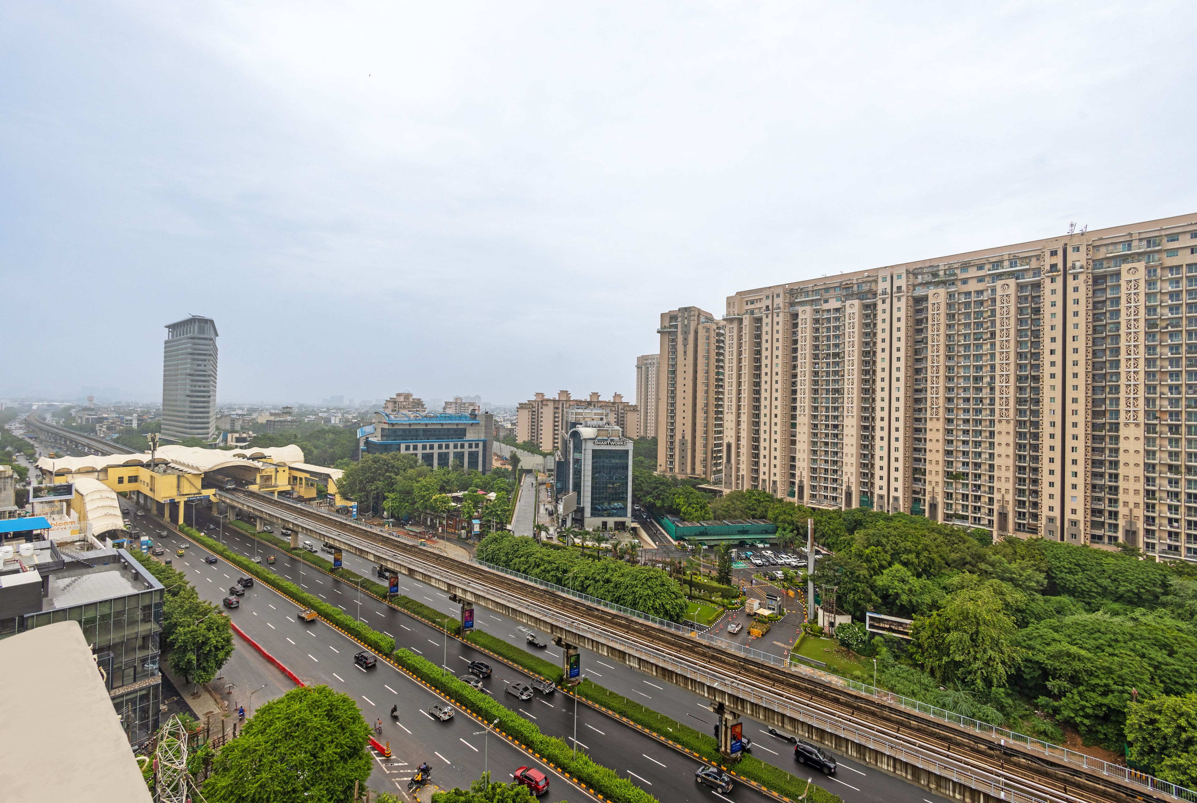 A multi-level highway with vehicles, surrounded by high-rise buildings and greenery.