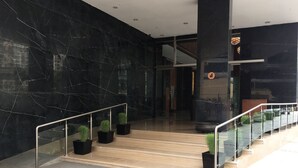 A modern lobby with marble walls, a wooden staircase, and potted plants. - The Anya Hotel, Gurgaon (Gurugram)