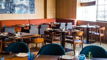 Un restaurante con varias mesas y cabinas, muebles de madera y un cuadro abstracto grande en la pared.