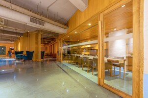 Ein modernes Interieur mit einer Glastrennwand, Holzvertäfelung und einem Essbereich mit Tischen und Stühlen.