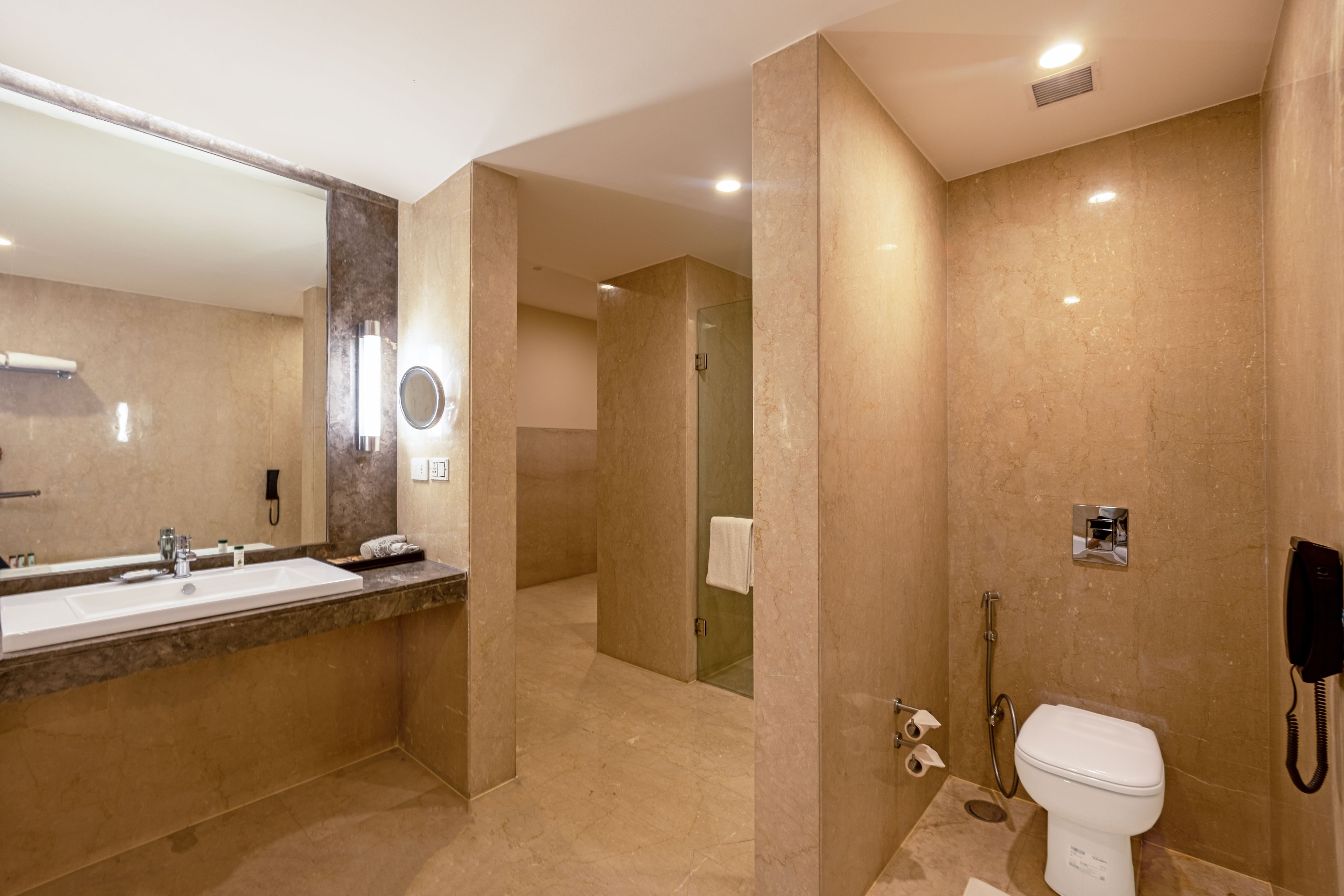 A modern bathroom with a large mirror, a sink, a toilet, and a shower area.