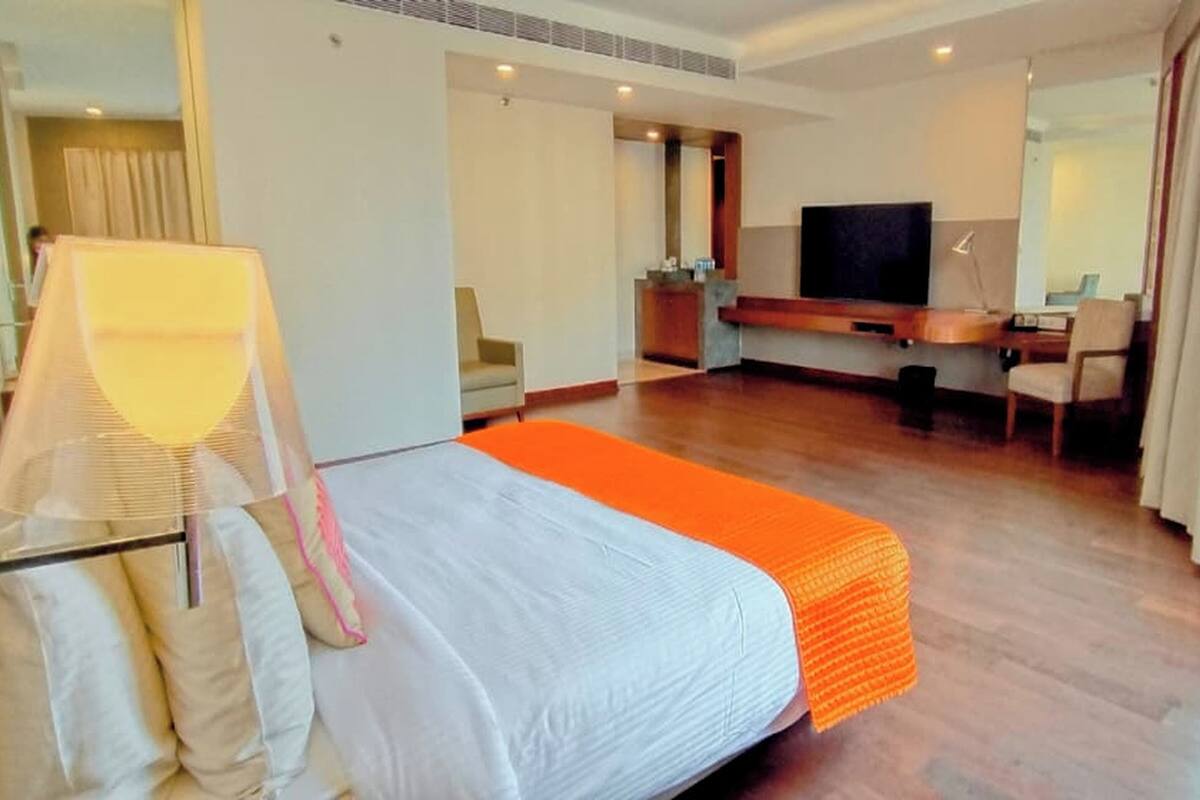 A hotel room with a bed, a desk, a chair, a TV, and a window with curtains.