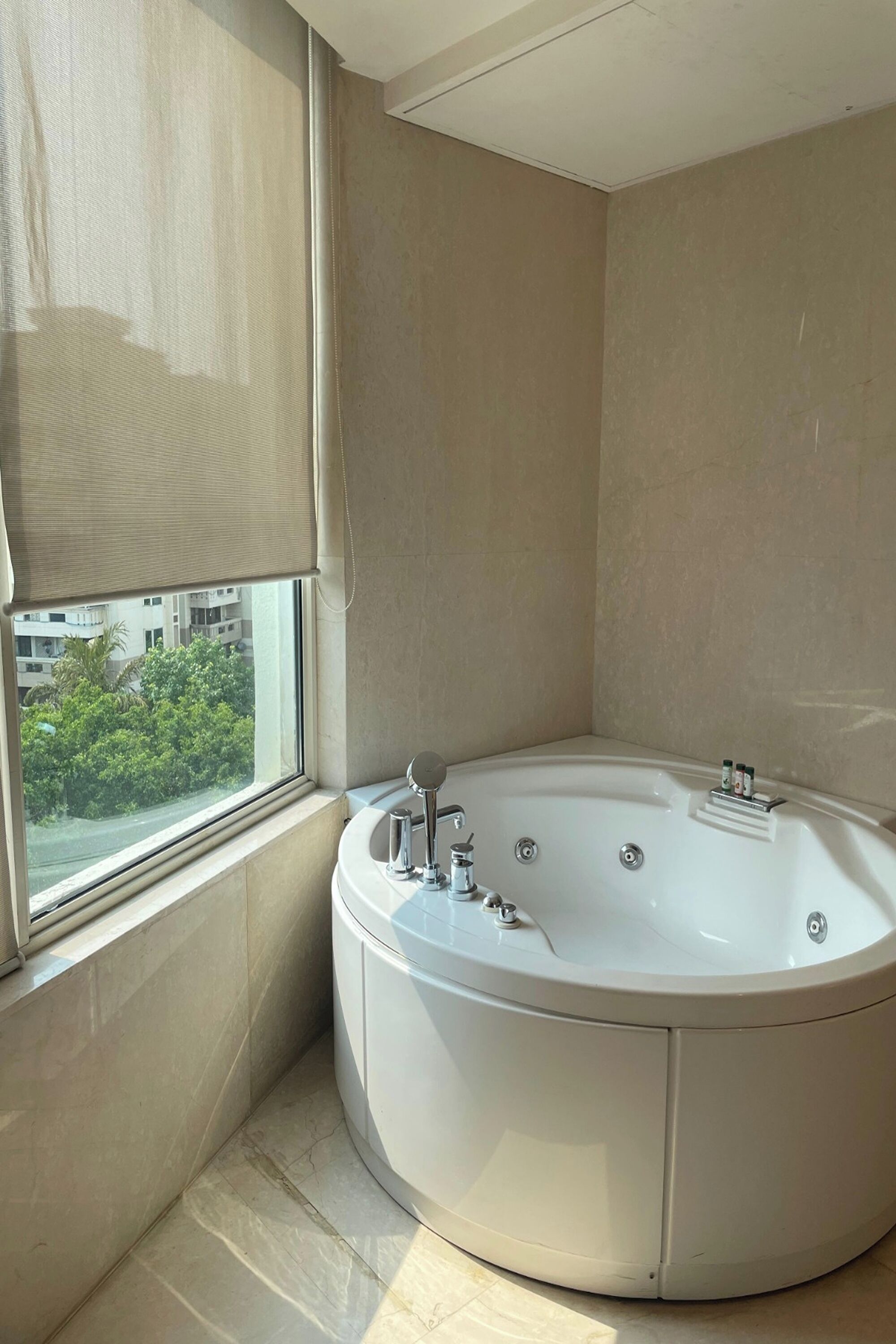 Un baño en esquina con una bañera grande, una ventana con vistas a zonas verdes y un ventilador de techo.