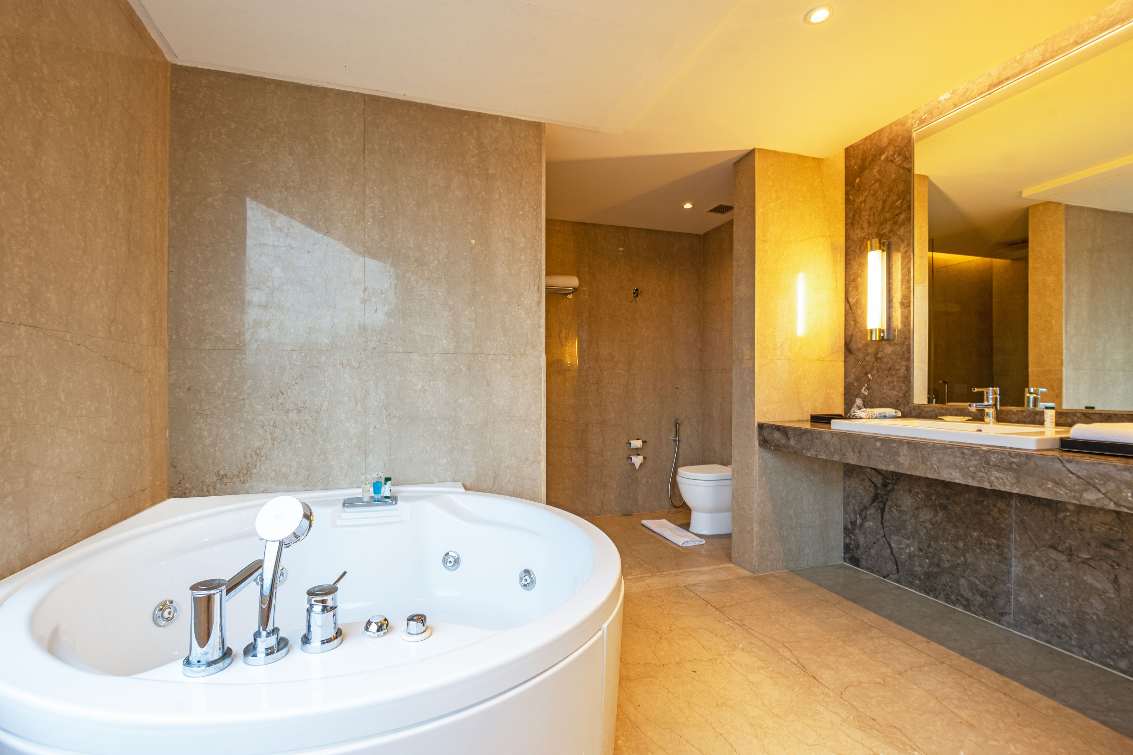 Un baño moderno con una bañera independiente, un espejo grande y una encimera de mármol.