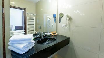 A modern bathroom with a black sink, white towels, a mirror, and a hairdryer.