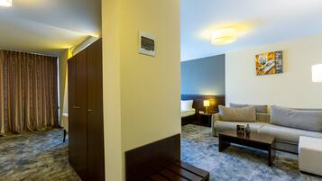 A hotel room with a bed, a sofa, a coffee table, a desk, and a lamp.
