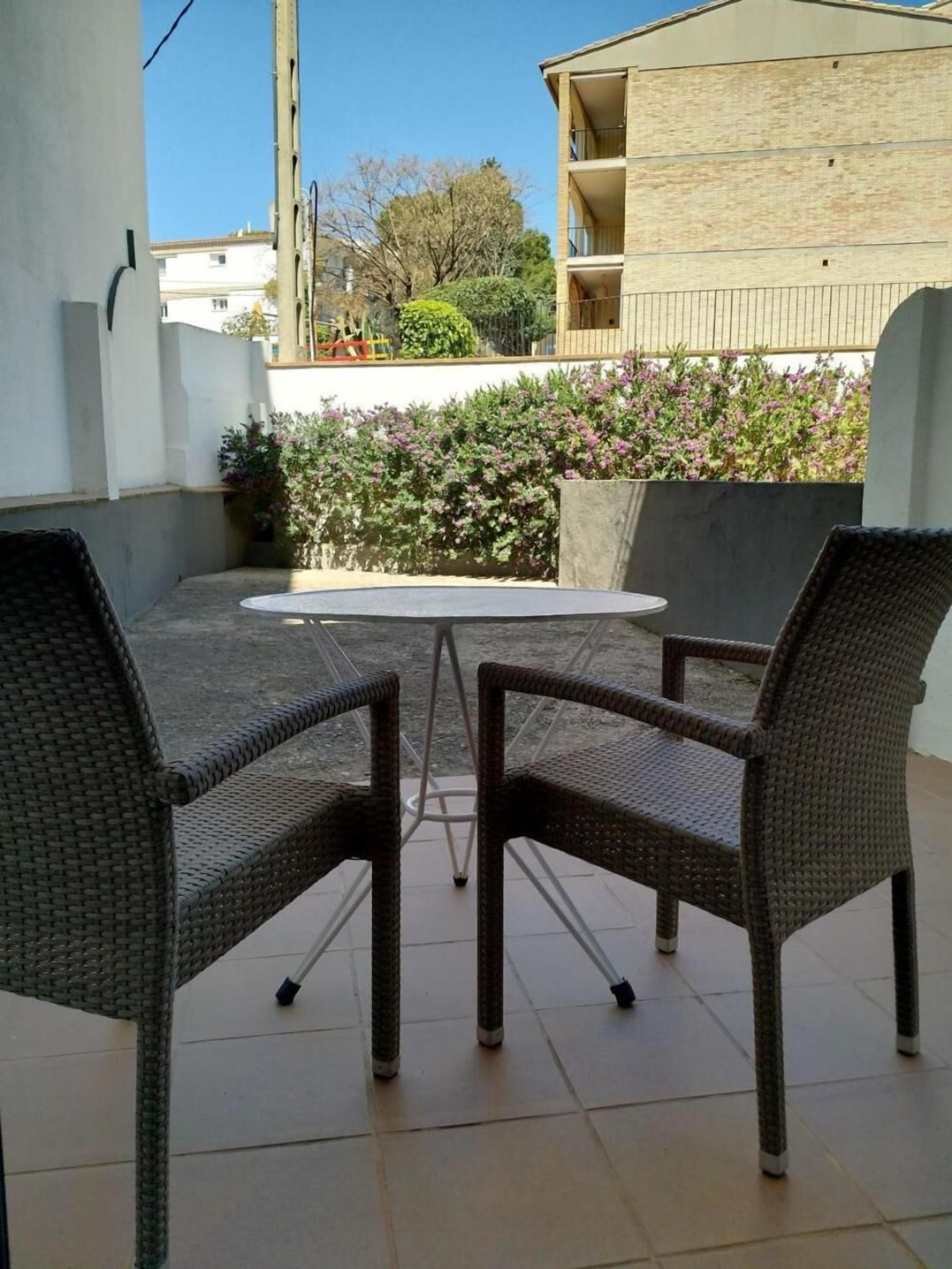 Eine Terrasse mit zwei Korbstühlen und einem kleinen runden Tisch.