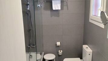 Un baño moderno con ducha de vidrio, inodoro, bidé y lavamanos.