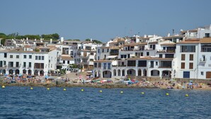 Un pueblo costero con edificios blancos, una playa y boyas amarillas en el agua.