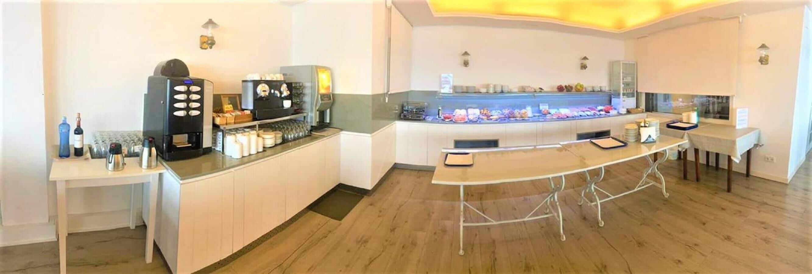 A modern hotel lobby with a coffee station, a buffet, and a seating area.