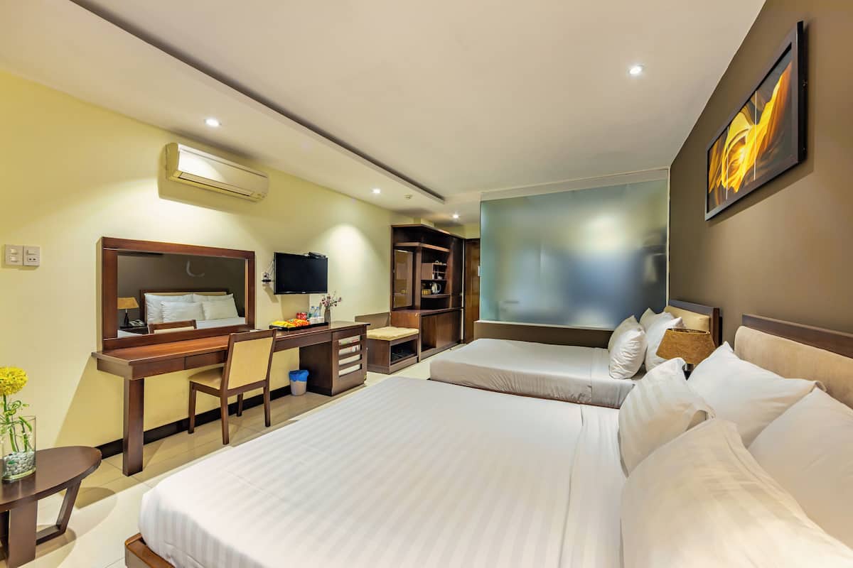 A hotel room with two beds, a desk, a chair, a TV, and a bookshelf.