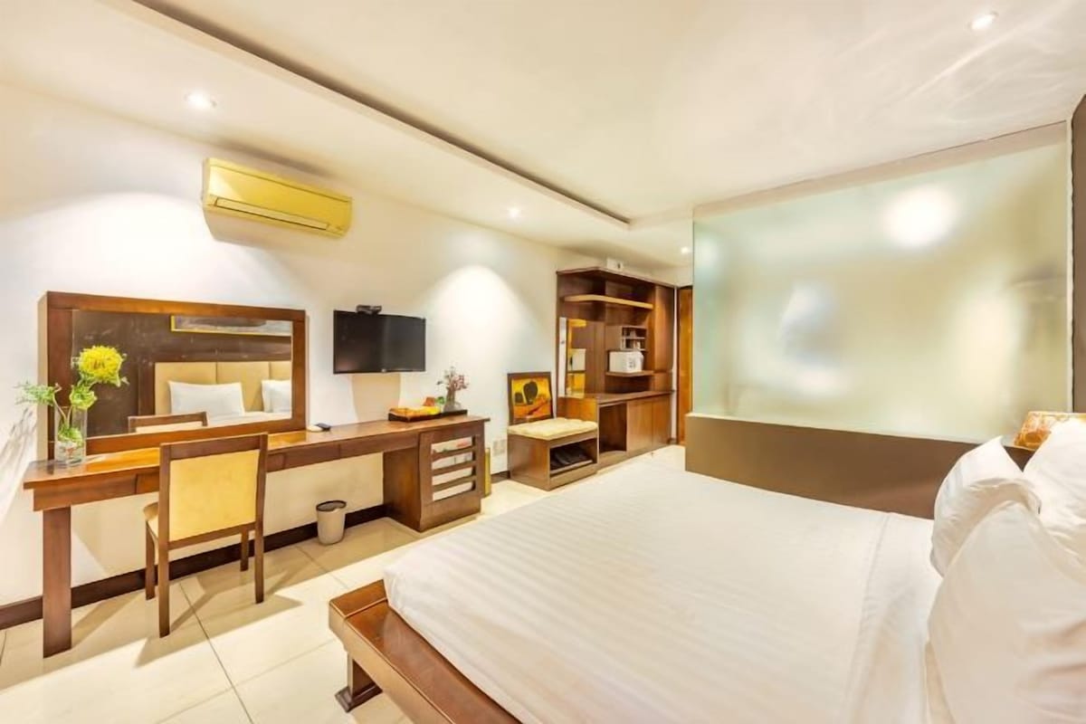 Camera d'albergo con letto, scrivania, sedia, televisore ed scaffali a muro.
