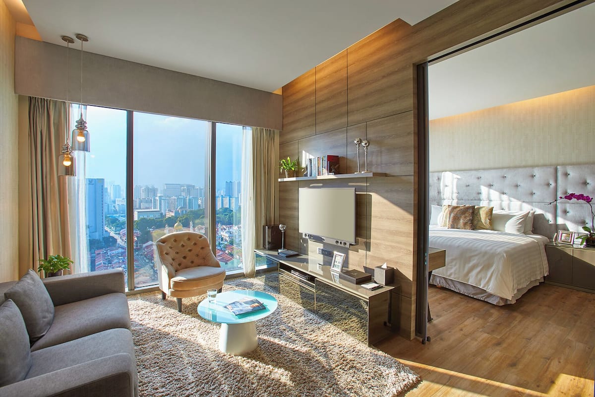 Een moderne hotelkamer met een groot raam, een bank, een bijzettafeltje, een bed en een televisie.