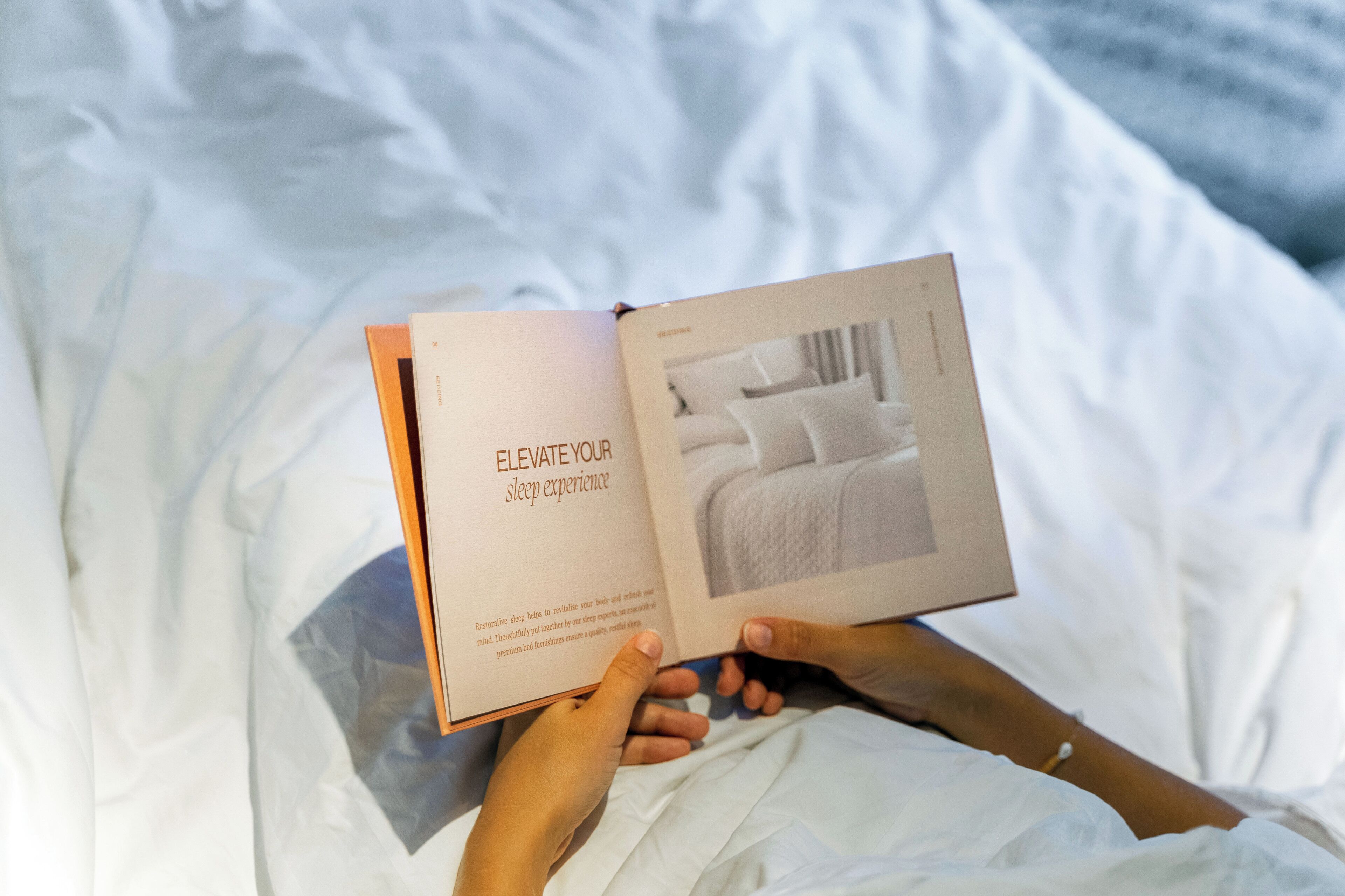 A person lying in bed reading a book with the text "Elevate Your Sleep Experience".