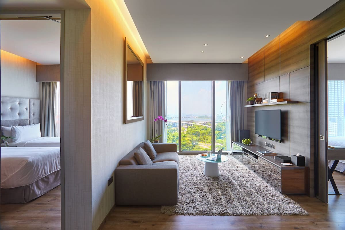 Een moderne hotelkamer met een groot bed, een bank, een televisie en uitzicht op een stadsbeeld.