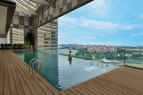 A rooftop infinity pool with a view of a cityscape and a bridge.