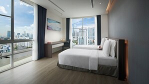 Ein modernes Hotelzimmer mit einem großen Bett, einem Schreibtisch und Blick auf die Skyline.