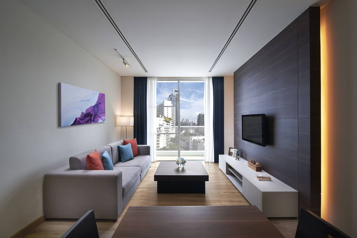 A modern living room with a sofa, coffee table, and a TV mounted on the wall.